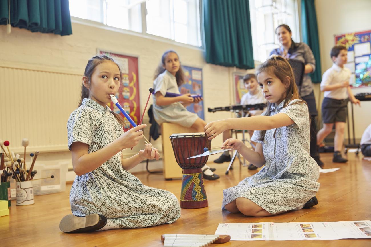 children play with instruments including a young girl playing recording