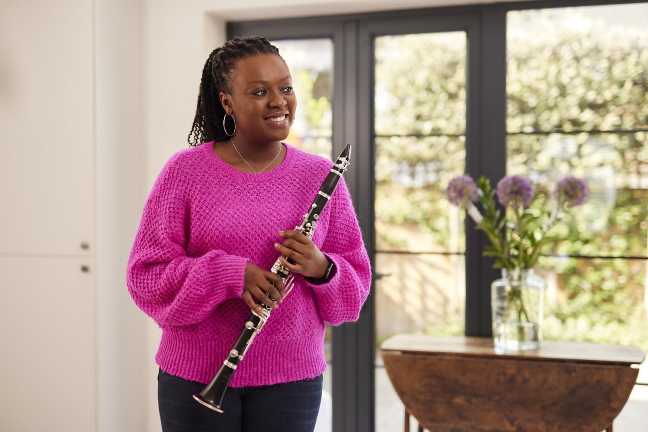 a woman holds her clarinet and smiles